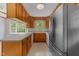 Traditional kitchen showcasing wood cabinets and white appliances beneath a window for natural lighting at 5529 Shadowbrook Dr, Raleigh, NC 27612