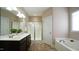 Bright bathroom featuring a double sink vanity, tiled floors, glass shower, and tub at 65 Wood Green Dr, Wendell, NC 27591
