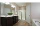 Bright bathroom featuring a double sink vanity, tiled floors, glass shower, and tub at 65 Wood Green Dr, Wendell, NC 27591