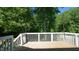 Wooden deck with white railing offers a private outdoor space surrounded by mature trees at 65 Wood Green Dr, Wendell, NC 27591