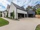 Striking exterior showcasing a white brick facade, a black metal roof and three-car garage with glass doors at 661 Manchester Dr, Raleigh, NC 27609