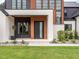 Modern facade with a solid front door, wood accents, white brick, and manicured landscaping at 661 Manchester Dr, Raleigh, NC 27609