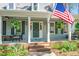Charming covered front porch with seating area, patriotic flag, and landscaped garden beds at 100 Mill Creek Dr, Fuquay Varina, NC 27526