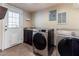 Laundry room with updated machines, tile floors, and access door at 103 Rex Pl, Louisburg, NC 27549