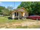Exterior view of a small yellow single-story home with a front porch and a red car parked to the side at 105 E Cole St, Dunn, NC 28334