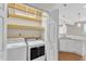 Bright laundry room featuring a front load washer and dryer and open shelving located next to the kitchen at 11035 Southwalk Ln, Raleigh, NC 27614
