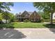 Elegant brick home featuring a manicured lawn, complemented by mature trees and lush landscaping at 112 Roseberry Way, Holly Springs, NC 27540