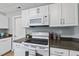 Bright kitchen with white cabinetry, modern appliances, and dark countertops at 112 Roseberry Way, Holly Springs, NC 27540