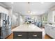 Open concept kitchen with a large island, stainless steel refrigerator, and view into the living room at 112 Roseberry Way, Holly Springs, NC 27540