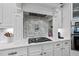 Modern cooktop with custom vent hood and cabinetry, plus backsplash with the words 'Y'all come eat' at 112 Roseberry Way, Holly Springs, NC 27540