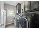 Laundry room featuring modern washer and dryer, storage cabinets, and a window at 112 Roseberry Way, Holly Springs, NC 27540