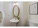 Cozy powder room features pedestal sink with gold fixtures, a gold-framed mirror, and decorative art at 113 Wilander Dr, Cary, NC 27511