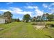 Expansive backyard featuring lush green lawn, a wooden deck structure and mature trees set under a vibrant blue sky with scattered clouds at 1169 Clayhole Rd, Dunn, NC 28334