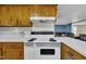 The kitchen features wood cabinets, white appliances, and a view into the living room at 1169 Clayhole Rd, Dunn, NC 28334