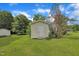 Exterior view of a small, well-maintained outbuilding with a white door and beige siding, set in a green lawn under a blue sky at 1169 Clayhole Rd, Dunn, NC 28334