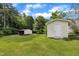 Spacious backyard featuring a shed and open-sided outbuilding on a lush lawn, surrounded by trees, under a partly cloudy blue sky at 1169 Clayhole Rd, Dunn, NC 28334