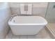 Elegant freestanding bathtub with chrome fixtures, set against marble-tiled walls and a glass-enclosed shower, enhanced by natural light at 1313 Dale St, Raleigh, NC 27605
