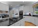 Bright kitchen with white cabinets, black countertops, stainless steel appliances, and a gas cooktop on the island at 191 Nc 56, Louisburg, NC 27549