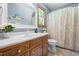 Bathroom featuring wood vanity, mirror, and tub-shower combo with patterned curtain at 2100 Fort Dr, Clayton, NC 27520