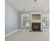 Bright living room features a modern fireplace and light-colored carpeting at 217 Braxcarr St, Holly Springs, NC 27540