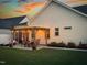 Evening backyard view featuring a pergola-covered patio with bistro lighting, dining set, lounge chairs, and manicured lawn at 24 Sweet Birch Row, Youngsville, NC 27596