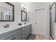 Modern bathroom featuring double sinks, gray cabinetry, a door, and a tiled shower at 24 Sweet Birch Row, Youngsville, NC 27596