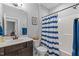 Full bathroom with wood vanity, toilet, shower-tub combination and blue and white shower curtain at 24 Sweet Birch Row, Youngsville, NC 27596