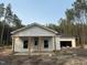 Charming single-story home with white siding, covered porch, and attached garage surrounded by natural landscaping at 240 Green Pines Estates Dr, Kenly, NC 27542