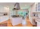 Spacious kitchen features a center island with a cooktop, stainless hood, and white cabinets with a built-in desk area at 313 Helmsdale Dr, Chapel Hill, NC 27517