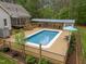 Aerial view of a backyard featuring a pool, deck, covered grilling area, and mature trees at 3653 Range Rd, Stem, NC 27581