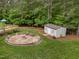 Spacious backyard with fire pit, shed, and greenery, ideal for outdoor activities and storage at 3653 Range Rd, Stem, NC 27581