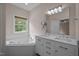 Bathroom with a bathtub, double sinks, marble countertops, and a large mirror at 3653 Range Rd, Stem, NC 27581