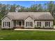 Home featuring a covered porch with green grass, brick accents, and dark shutters at 3653 Range Rd, Stem, NC 27581