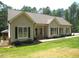 Inviting front yard featuring lush grass, decorative shrubs, and a charming covered front porch at 3653 Range Rd, Stem, NC 27581