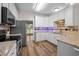 Kitchen with stainless steel appliances, white cabinets, granite counters and wood floors at 3653 Range Rd, Stem, NC 27581