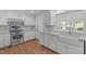 Updated kitchen features white cabinetry, subway tile backsplash, stainless steel appliances and a farmhouse sink at 4830 North Hills, Raleigh, NC 27612