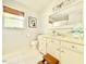 Bright bathroom with vanity, toilet, mirror, a woven shade, and a window for natural light at 5021 Lansdowne Dr, Durham, NC 27712