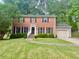 Charming two-story red brick home with a well-manicured lawn and mature trees at 5021 Lansdowne Dr, Durham, NC 27712