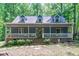 Charming home featuring a welcoming front porch, dormer windows, and lush landscaping surrounded by mature trees at 603 Gentry Ln, Hillsborough, NC 27278