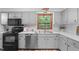 Bright kitchen with stainless appliances, light gray cabinets, wood-trimmed window, and durable modern flooring at 603 Gentry Ln, Hillsborough, NC 27278