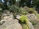 Landscaped backyard featuring stone steps, green plants, rock wall, and lush trees at 606 Chalice St, Durham, NC 27705