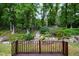 View of backyard featuring a stone wall, wooden fence and steps leading up a gentle slope covered in trees and foliage at 606 Chalice St, Durham, NC 27705