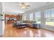 Open living room with hardwood floors, large windows, ceiling fan, and modern furnishings at 713 Apalachia Lake Dr, Fuquay Varina, NC 27526