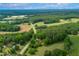 An aerial shot of the property featuring a tree-lined road, open fields, and a charming home with a red roof at 774 Salem Church Rd, Sanford, NC 27330