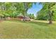 View of the backyard, featuring a spacious lawn, privacy fence, mature trees, and a brick home at 774 Salem Church Rd, Sanford, NC 27330
