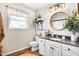 Bathroom with a round mirror, granite countertops, white cabinets and hardwood floors at 1199 Cesar Ct, Graham, NC 27253