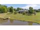 Charming exterior view of the house by a serene pond, complemented by a well-manicured lawn and mature trees at 1199 Cesar Ct, Graham, NC 27253