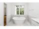 A bathtub under a window that looks out to a forest, next to a vanity in a bathroom at 1301 Doylin Dr, Cary, NC 27511
