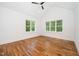 Bright bedroom with hardwood floors, ceiling fan, and natural light from two large windows at 1301 Doylin Dr, Cary, NC 27511