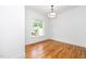 The empty bedroom has a view of the front yard, and hardwood floors and the light fixture at 1301 Doylin Dr, Cary, NC 27511